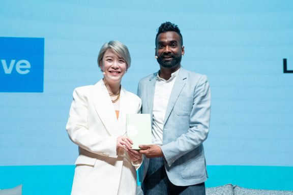 Two people standing together, smiling and holding a certificate at a formal event.