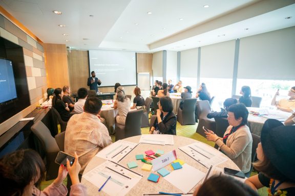 Rama leading a workshop in front of 15 people