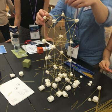 A group of people building a tower out of marshmallows and spaghetti