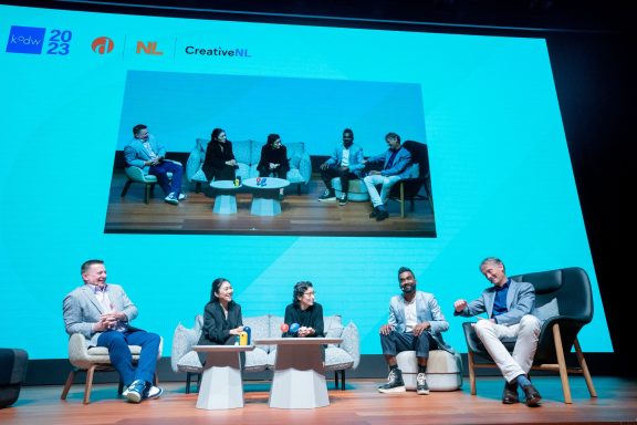A panel discussion featuring five speakers seated in a modern conference setting.